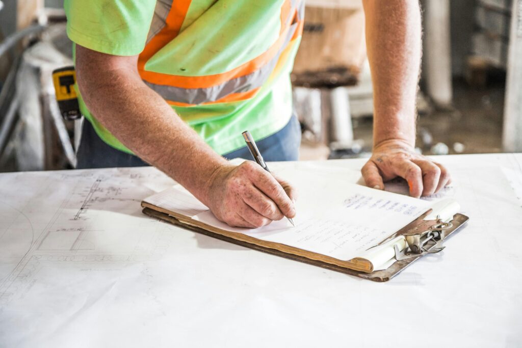 pexels-photo-544965-544965-1 A construction worker writes notes on a clipboard at a construction site, emphasizing planning and precision.