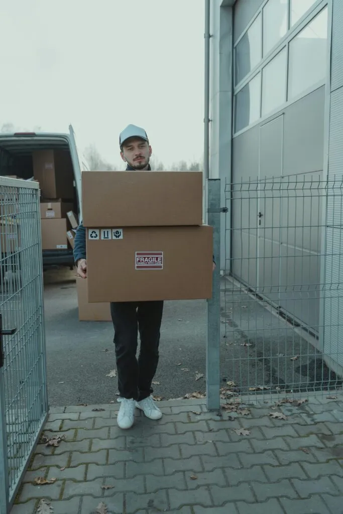 pexels-photo-6169176-6169176-1 Man delivering cardboard boxes in an outdoor setting wearing casual attire.