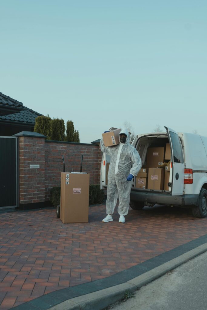 pexels-photo-6170465-6170465 A delivery person in protective gear unloading packages from a van outdoors.