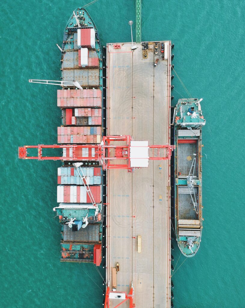 pexels-photo-7548828-7548828 Aerial shot of cargo ships docked at a harbor with cranes and containers.