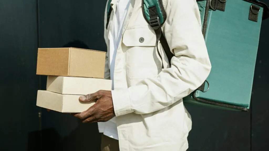 pexels-photo-8989312-8989312 Close-up of a delivery person holding cardboard packages outdoors, showcasing modern urban logistics.